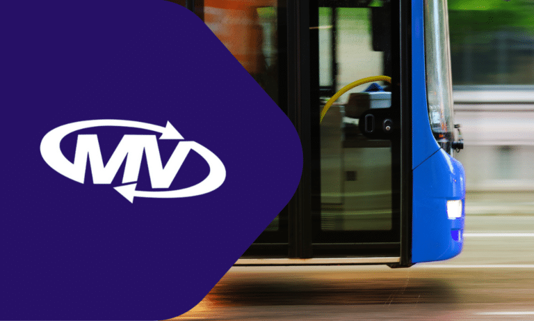 MVD public transit bus featuring the company's purple and blue branding with distinctive logo and modern design parked at a station platform.