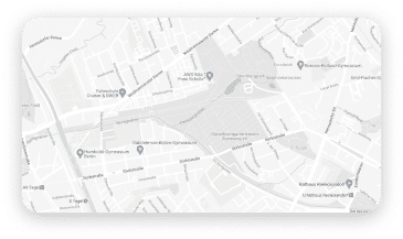 A light gray street map displaying urban roadways, building outlines, and navigation markers across a residential or downtown area with minimal text visibility due to the faded design.