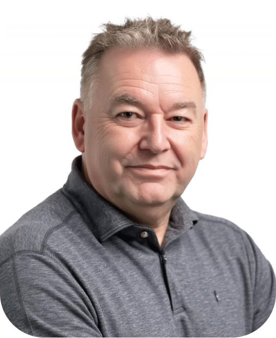Professional headshot of a middle-aged man wearing a gray button-up shirt against a white background. He has short, light brown hair styled upward and displays a confident, friendly expression.