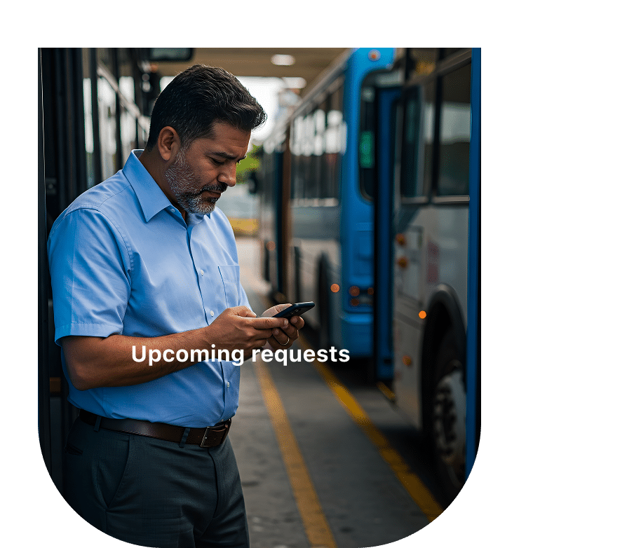 Bus driver in blue uniform checks mobile phone while standing in transit depot. Text overlay reads "Upcoming requests" indicating a ride-sharing or dispatch application interface.
