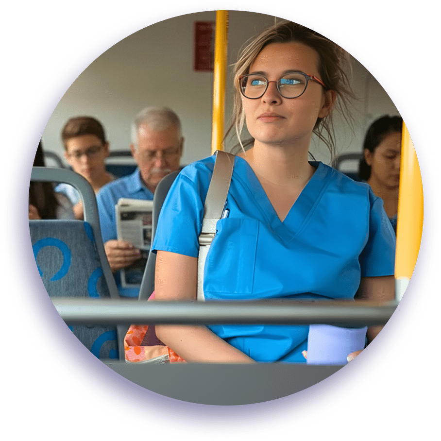 Young woman wearing glasses and blue medical scrubs on public transport, with colleagues visible in the background during a commute.
