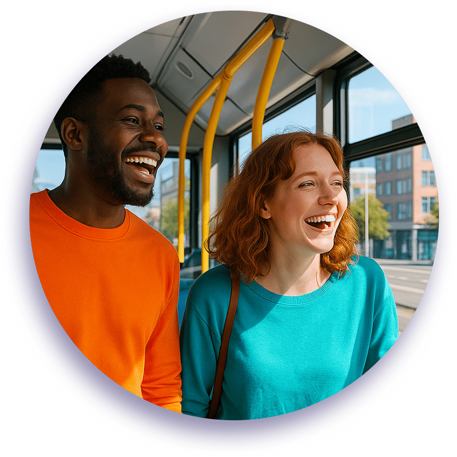 Two happy passengers laugh together on a public transit bus with yellow poles, wearing bright orange and teal sweaters while enjoying a sunny city ride.