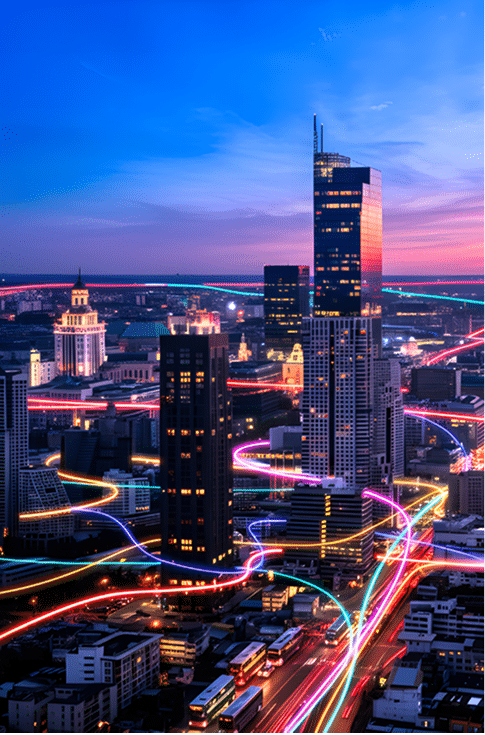 Vibrant cityscape at twilight with illuminated skyscrapers and light trails from busy highways creating dynamic red and blue streaks across the urban landscape.