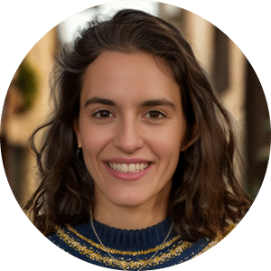 Portrait of a smiling young woman with long dark wavy hair wearing a dark blue sweater with gold trim detail, photographed in a circular crop format.