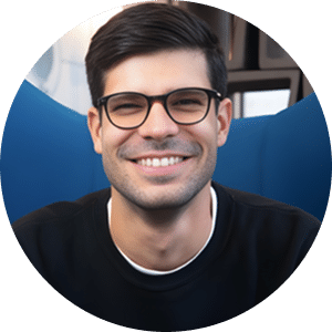 Professional headshot of a smiling man wearing black-framed glasses and a dark shirt against a blue circular background. His approachable expression and polished appearance suggest a corporate