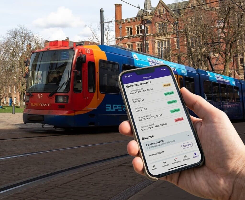 Hand holding smartphone displaying transit employee requests app with pending and approved time-off entries, with colorful Supertram tram number 113 in background on urban street.