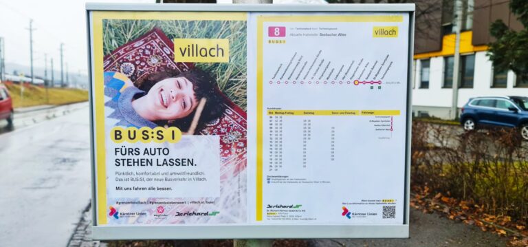 Villach bus shelter displaying BUS:SI transit advertisement with schedule information and route map for the Seebacher Allee bus line in Austria.