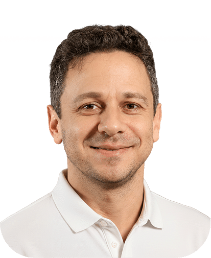 Professional headshot of a middle-aged man with dark hair wearing a white collared shirt against a white background. He has a friendly smile and appears to be in his 40s or 50s.