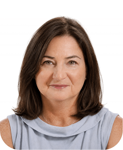 Professional headshot of a middle-aged woman with shoulder-length brown hair wearing a light gray sleeveless top against a white background.